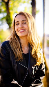 Cheerful woman in a leather jacket enjoying a sunny day outside.